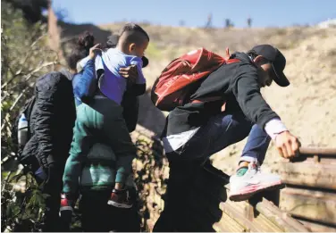  ?? Mario Tama / Getty Images ?? Migrants cross the U.S.-Mexico border in Tijuana on Tuesday before surrenderi­ng to the U.S. Border Patrol. Migrants are to stay in Mexico under the new policy while their U.S. claims are being considered.