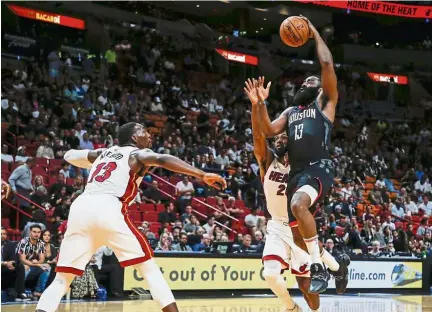  ??  ?? Up, up and away: Houston Rockets guard James Harden (right) goes high to score past Miami Heat defenders Bam Adebayo (left) and Justise Winslow during the first quarter of an NBA pre-season basketball game on Friday. Houston won 144-133. — AP