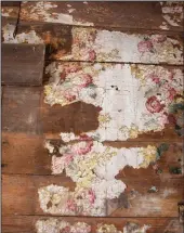  ??  ?? Remnants of floral wallpaper cling on a bare wood wall.