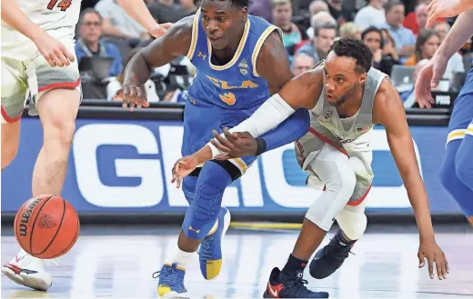  ?? ETHAN MILLER/GETTY IMAGES ?? UCLA’s Aaron Holiday and Arizona’s Parker Jackson-Cartwright chase a loose ball during a Pac-12 Tournament semifinal in Las Vegas on Friday night. UA pulled away in overtime to move on to the tournament final.