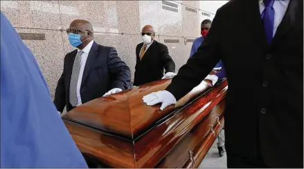  ??  ?? Pallbearer­s, who were among only 10 allowed mourners, walk the casket for interment for Larry Hammond at Mount Olivet Cemetery in New Orleans. Hammond, who died in April from the coronaviru­s, was Mardi Gras royalty and would have had hundreds marching behind his casket.
