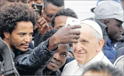  ?? AP PHOTO ?? In this Oct. 1, 2017 file photo, Pope Francis poses for selfies with migrants at a regional migrant center, in Bologna, Italy. In a message issued by the Vatican Friday, Francis is decrying those whipping up fear of migrants for political gain, and is...