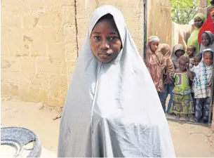  ?? AFP ?? Hassana Mohammed, 13, who scaled a fence to escape an alleged Boko Haram attack on her Government Girls Science and Technical College, stands outside her home in Dapchi, Nigeria, on Thursday.