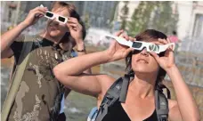  ?? ILNAR SALAKHIEV, AP ?? People check their eclipse glasses before a solar eclipse in the Siberian city of Novosibirs­k in July 2008.