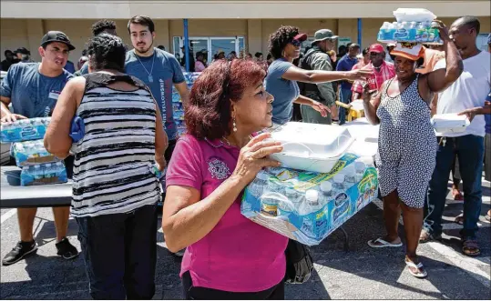  ?? PHOTOS BY ALLEN EYESTONE / THE PALM BEACH POST ?? Residents pick up meals and water Wednesday during a mass distributi­on at Northwest Second Street and W Canal Street in Belle Glade. The food and water were handed out in partnershi­p with Christ Fellowship Church, PBC Food Bank, Home Depot, Sugar Cane...