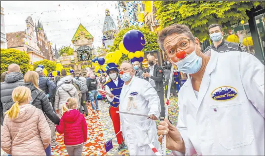  ?? Philipp von Ditfurth The Associated Press ?? Visitors to Europa-park walk through an avenue while employees stand guard and confetti rains down Friday in Rust, Germany.