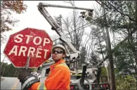  ?? (File Photo/AP/Robert F. Bukaty) ?? Canadian lineman Noah Clowater holds a bilingual stop sign Nov. 1, 2017, while his coworkers restore power in Yarmouth, Maine.