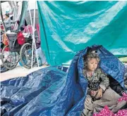  ?? [AP PHOTO] ?? A girl who traveled with a caravan of Central American migrants awakens Tuesday where the group set up camp to wait for access to request asylum in the U.S., outside the El Chaparral port of entry building at the US-Mexico border in Tijuana, Mexico.