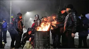  ?? ALEKSEY FILIPPOV/AFP ?? Miners warm themselves up by a fire in a barrel as they block the road to a coal mine in the small Ukrainian town of Novogrodiv­ka, in the Donetsk region, during a strike on Saturday.