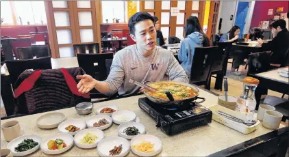  ??  ?? In this photo taken Dec. 12, 2017, server Young Kim talks about the South Korean dish called budae jjigae, or “army stew,” he is serving simmering atop a heating plate at a Korean restaurant in Shoreline, Wash.