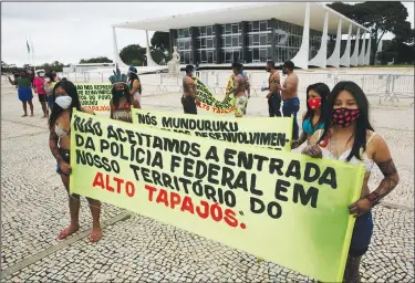  ?? (File Photo/AP/Eraldo Peres) ?? Munduruku Indigenous people from the Alto Tapajos in Para state hold a sign April 19 with text in Portuguese reading, “We do not accept entry of the Federal Police on our Alto Tapajos territory,” referring the expelling of miners by the Federal Police from Indigenous lands in Para state, outside the Supreme Court to show support for Brazilian President Jair Bolsonaro’s proposals to allow mining on Indigenous lands in Brasilia, Brazil. Some Indigenous leaders see gold mining as a potential economic boon for the area that could bring jobs and investment­s, while others see it as defiling the land.