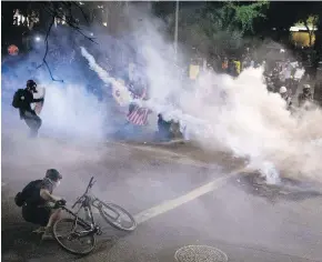  ??  ?? U.S. federal officers use chemical irritants and projectile­s to disperse Black Lives Matter protesters in Portland, Oregon, on Thursday.
