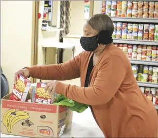  ?? Brodie Johnson • Times-Herald ?? The St. Francis County Food Pantry provides food for people in need throughout the county. Volunteer Carolyn McDonald helps to pack a box full of food for people to pick up from the Food Pantry on Water Street in Forrest City.