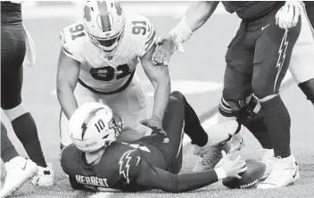  ?? TIMOTHY T LUDWIG GETTY IMAGES ?? Chargers QB Justin Herbert recovers his own fumble during the fourth quarter against the Bills.