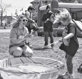  ?? RICHARD MACKENZIE PHOTOS ?? Event helper Maia Sloan celebrates Millie Parker having success at a fishing game.