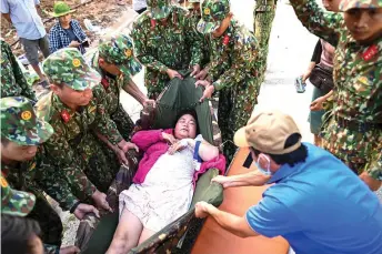  ?? — AFP photos ?? Military personnel carry an injured woman onto a stretcher a er she was rescued from a landslide in Tra Leng commune in central Vietnam’s Quang Nam province.