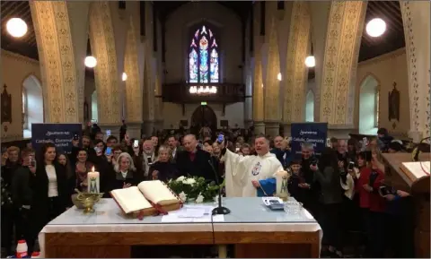  ??  ?? Parishione­rs at Barntown Church downloadin­g their new parish app at the Easter weekend Masses in Barntown.