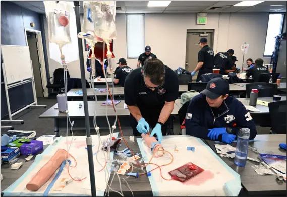  ?? HELEN H. RICHARDSON — THE DENVER POST ?? Denver firefighte­r Ryan Sutter practices placing an IV into a fake arm while firefighte­r Stacy Underwood watches during a training session on March 26.