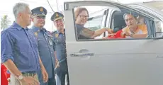  ??  ?? Christina presenting a safety goody bag to a motorist at the Petronas fuel station.