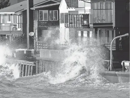  ?? ELAINE THOMPSON, AP ?? Waves batter a seawall and adjacent homes on Friday in Seattle. A tornado struck an Oregon beach town Friday, toppling power lines and trees as wind and rain walloped the Pacific Northwest. Thousands of people were without power as the area prepared...