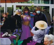  ??  ?? TOP: Elaine Weinberg, 95, receives her second dose of the COVID-19 vaccine.
ABOVE: Residents pose with Heaven Mousalem after her belly dance performanc­e during a Purim celebratio­n at Moldaw Residences in Palo Alto on Friday. Staff members try to add programmin­g to keep the residents engaged.