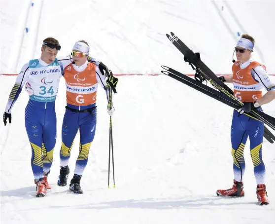 ?? Bild: JESSICA GOW/TT ?? SEKUNDER FRÅN PALLEN. Zebastian Modin, till vänster, i målfållan efter medaljmiss­en på 20 kilometer. Guiderna Robin Bryntesson, håller om Modin, och Johannes Andersson försöker trösta.