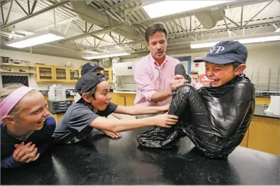  ?? GABRIELA CAMPOS/THE NEW MEXICAN ?? Pierce Trevisani, right, participat­es in a vacuum-sealing experiment in a demo science class Friday during Santa Fe Prep’s open house.