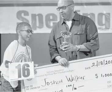  ?? Yi-Chin Lee photos / Houston Chronicle ?? Joshua Walker receives a $1,000 scholarshi­p and the first-place trophy Saturday at the African American National Spelling Bee from Robert Garner, founder of the competitio­n.