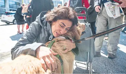  ?? CARLOS OSORIO PHOTOS/TORONTO STAR ?? Marjan Iravani hugs Buddy the golden retriever therapy dog from St. John's Ambulance at Mel Lastman Square on Thursday.