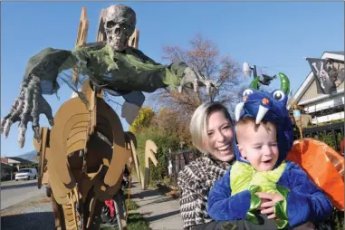  ?? GARY NYLANDER/The Daily Courier ?? Natasha Heidebrech­t holds her son, Eli Shorter, 3, dressed as a dragon, in front of a home with an extensive Halloween display at 682 Bay Ave. in Kelowna. The house is sure to be a popular stop for trick-or-treaters tonight.