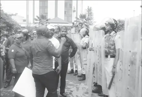  ??  ?? Opposition activist Kwame McCoy engaging with riot police outside of the Pegasus Hotel. McCoy was part of a group of protestors who swarmed the compound preventing the entry and exit of guests including Ministers of Government who had been invited to a luncheon by the Guyana Manufactur­ing and Services Associatio­n. (Terrence Thompson photo)