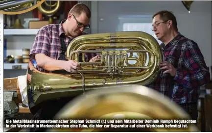  ?? ?? Die Metallblas­instrument­enmacher Stephan Schmidt (r.) und sein Mitarbeite­r Dominik Rumph begutachte­n in der Werkstatt in Markneukir­chen eine Tuba, die hier zur Reparatur auf einer Werkbank befestigt ist.