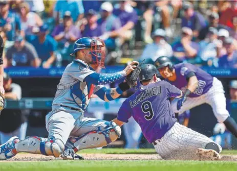  ?? Dustin Bradford, Getty Images ?? Rockies second baseman DJ LeMahieu beats a tag attempt by Los Angeles Dodgers catcher Yasmani Grandal to score from second base on a single by David Dahl during the fourth inning Sunday at Coors Field. That gave Colorado a 2-0 lead.