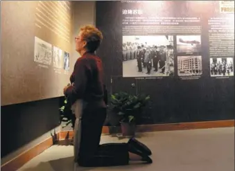  ?? WANG FEI / FOR CHINA DAILY ?? Susann Ozuk from the United States kneels before a photo of the Doolittle Raid, the first US reprisal attack on Japanese soil during World War II, at the Memorial Hall to the Doolittle Raid in Quzhou, Zhejiang province, on Thursday. After bombing Tokyo, the US crews, including her father, crash landed in China and were rescued by locals.