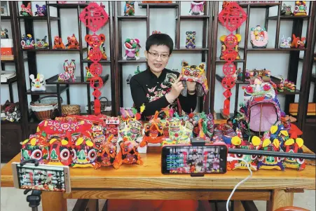  ??  ?? Above: A member from Jiaodong Folk Art Museum in Shandong province’s Yantai holds an online training about making tiger-shaped hats, a local handicraft.