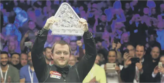  ??  ?? 2 Mark Allen hoists his trophy after defeating Kyren Wilson 10-7 to become the Dafabet Masters champion on Sunday.
