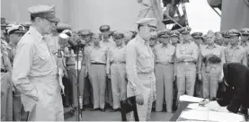  ??  ?? In this 2 September 1945, file photo, US General Douglas MacArthur, left, watches as the foreign minister Manoru Shigemitsu of Japan signs the surrender document aboard the USS Missouri on Tokyo Bay. Lt. General Richard K. Sutherland, center, witnesses the ceremony marking the end of World War II with other American and British officers in background.