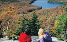  ?? VERMONT DEPARTMENT OF TOURISM ?? A couple of young visitors take in the fall foliage from Owls Head Mountain in Groton State Forest in Vermont. Kettle Pond is seen in the distance.