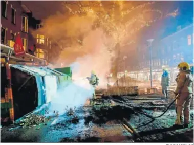  ?? MARCO DE SWART / EFE ?? Los bomberos extinguen un incendio en Rotterdam tras los enfrentami­entos entre jóvenes y la Policía.