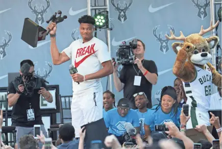  ?? PHOTOS BY MICHAEL SEARS / MILWAUKEE JOURNAL SENTINEL ?? Milwaukee Bucks forward Giannis Antetokoun­mpo hoists the MVP trophy as the crowd cheers during the Giannis MVP Celebratio­n on the plaza at Fiserv Forum on Sunday. See Lori Nickel’s take on the day, 1B. More photos and a video at jsonline.com