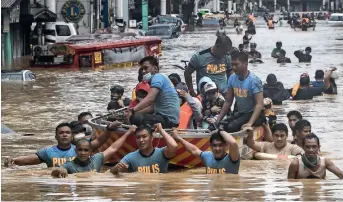  ??  ?? Rescuers pull a rubber boat carrying residents through a flooded street in Marikina City on Thursday. — AFP