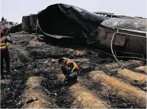  ??  ?? Rescue workers examine the grim site after the oil tanker explosion