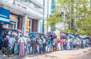  ?? THE NEW YORK TIMES ?? People line up to withdraw cash in March in Yangon, Myanmar. Since the military seized power in a coup six months ago, the Southeast Asian nation has been brought to its knees by a critical lack of cash.