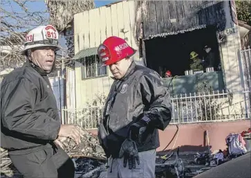  ?? Photograph­s by Irfan Khan Los Angeles Times ?? BATTALION CHIEF Richard Fields, left, and arson investigat­or Robert McCloud assess the scene of Monday’s fire that trapped the children, ages 7 and younger, in the bungalow on West Manchester Avenue.