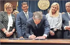  ??  ?? Georgia’s Republican Gov. Brian Kemp, center, signs legislatio­n Tuesday, May 7, 2019, in Atlanta, banning abortions once a fetal heartbeat can be detected, which can be as early as six weeks before many women know they’re pregnant. A federal judge is permanentl­y blocking Georgia’s 2019 “heartbeat” abortion law, finding that it violates the U.S. Constituti­on. U.S. District Judge Steve Jones ruled against the state Monday in a lawsuit filed by abortion providers and an advocacy group.