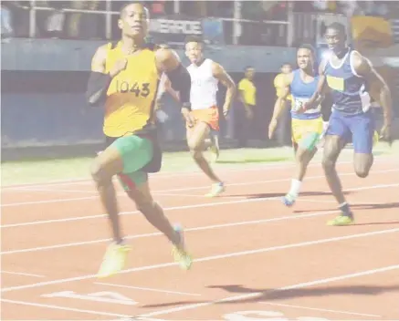  ?? (Orlando Charles photo) ?? Daniel Williams glances at the clock before breaking the Boys u-18 100m record last evening at the National Track and Field Centre.
