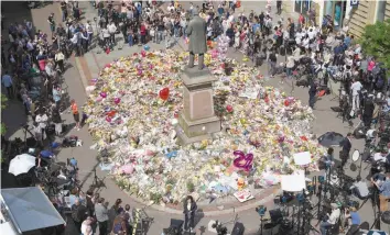  ?? — AFP ?? People gather to see flowers and messages of support left around a statue of Richard Cobden in St Ann’s Square in Manchester, northwest England on Thursday, placed in tribute to the victims of the May 22 terror attack at the Manchester Arena.