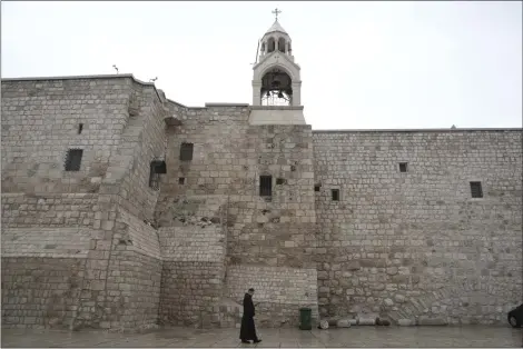  ?? MAHMOUD ILLEAN-ASSOCIATED PRESS ?? A priest walks by the Church of the Nativity, traditiona­lly believed to be the birthplace of Jesus, on Christmas Eve, in the West Bank city of Bethlehem, Dec. 24.