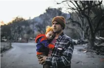  ??  ?? Elijah Field embraces son Brady, 2, after going through his mother’s destroyed belongings off Honey Run Road.