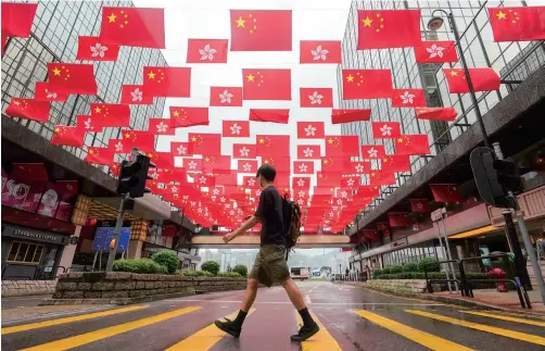  ??  ?? 6月29日，在香港尖沙咀一条街上，中华人民共和国国旗和­香港特别行政区区旗一­起迎风飘扬。“七一”临近，香港街头出现许多“贺建党百年”“庆香港回归”的喜庆元素。 东方IC图